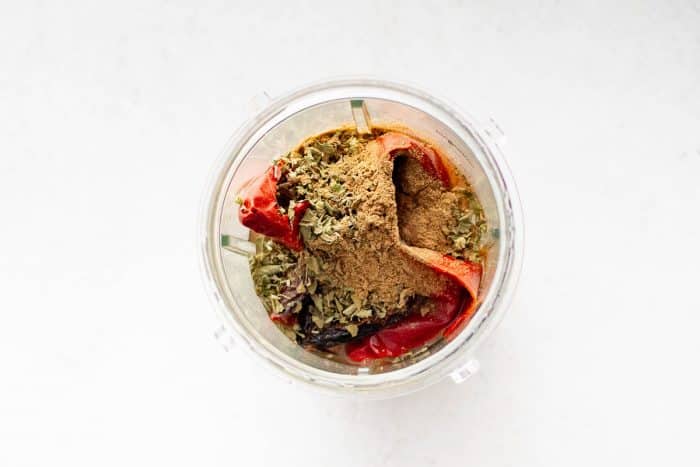 Soaked dried chili peppers, Mexican oregano, and ground cumin inside a blender.