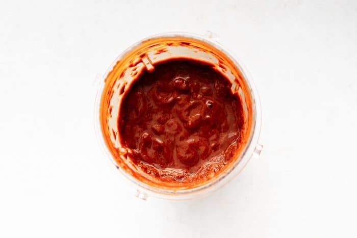 Smooth red chili paste in a blender after blending dried peppers and spices.