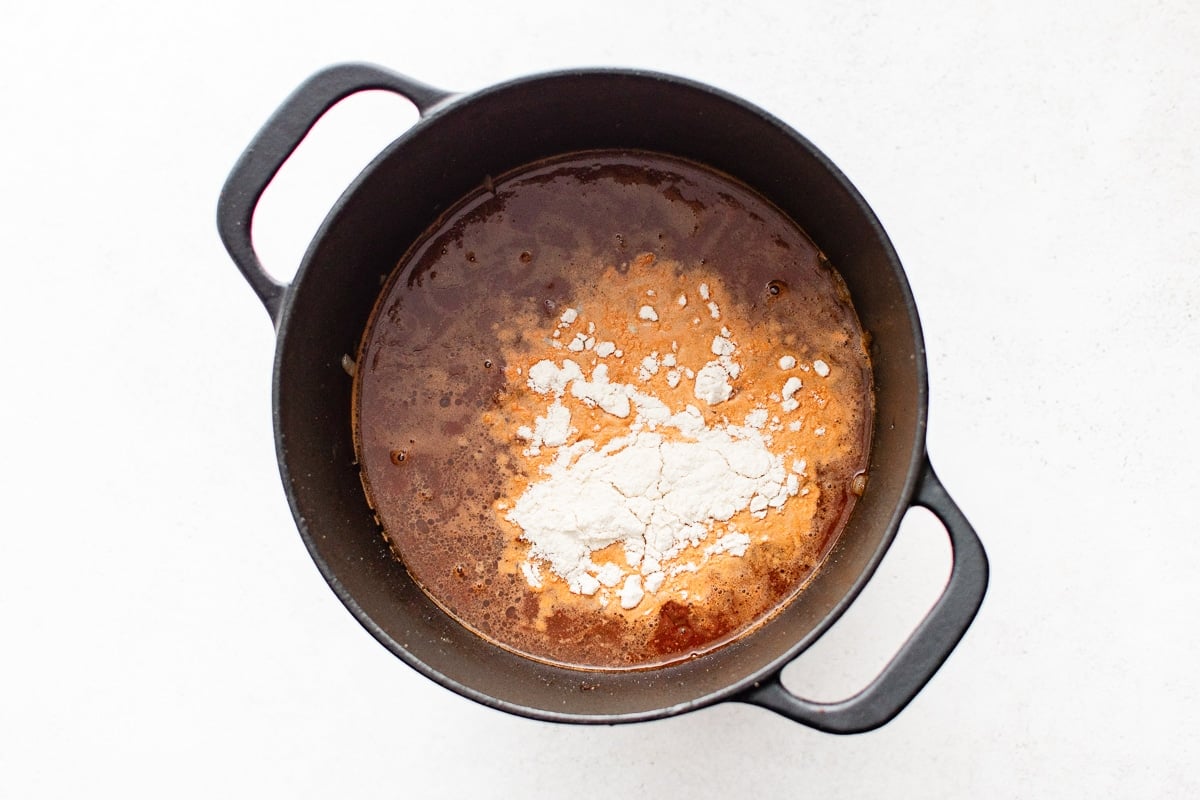 A Dutch oven filled with broth and beef, with masa harina sprinkled on top.