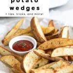Crispy air fryer potato wedges served on parchment paper with ketchup, styled with the text overlay โsuper crispy air fryer potato wedges + tips, tricks, and more!โ for Pinterest.