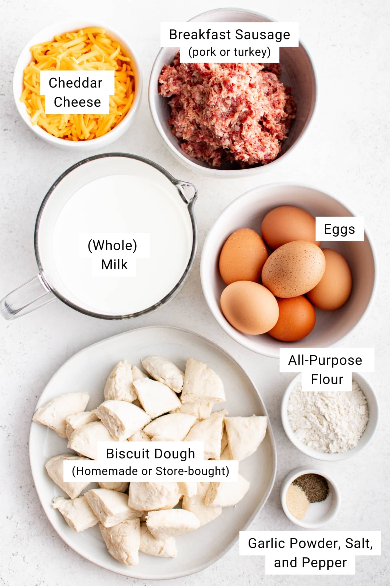 ngredients for biscuits and gravy casserole including sausage, eggs, cheese, milk, flour, biscuit dough, salt, pepper, and garlic powder.