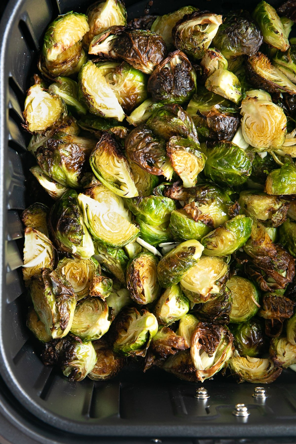 Crispy air-fried Brussels sprouts in a black air fryer basket.