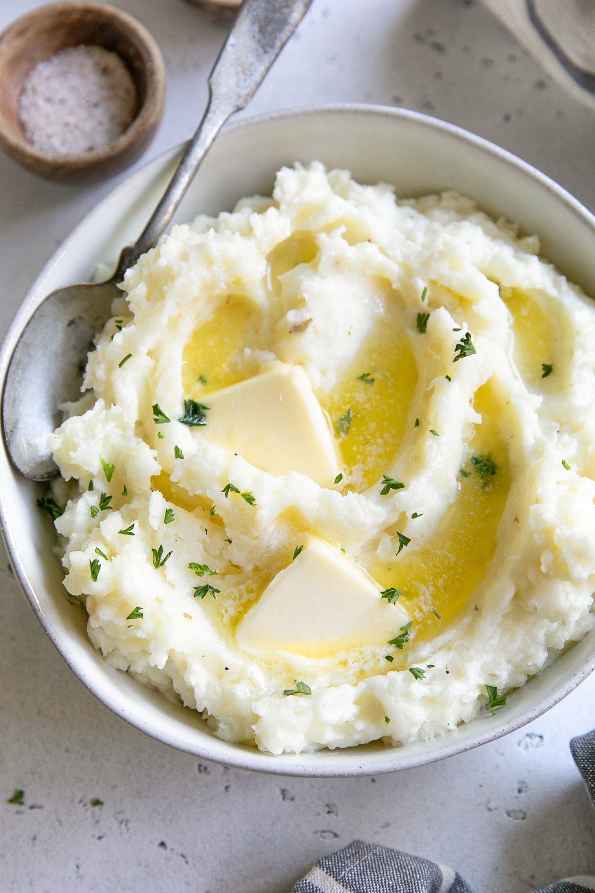 Bowl of creamy mashed potatoes with melted butter and chopped parsley - a must-have Thanksgiving side dish.