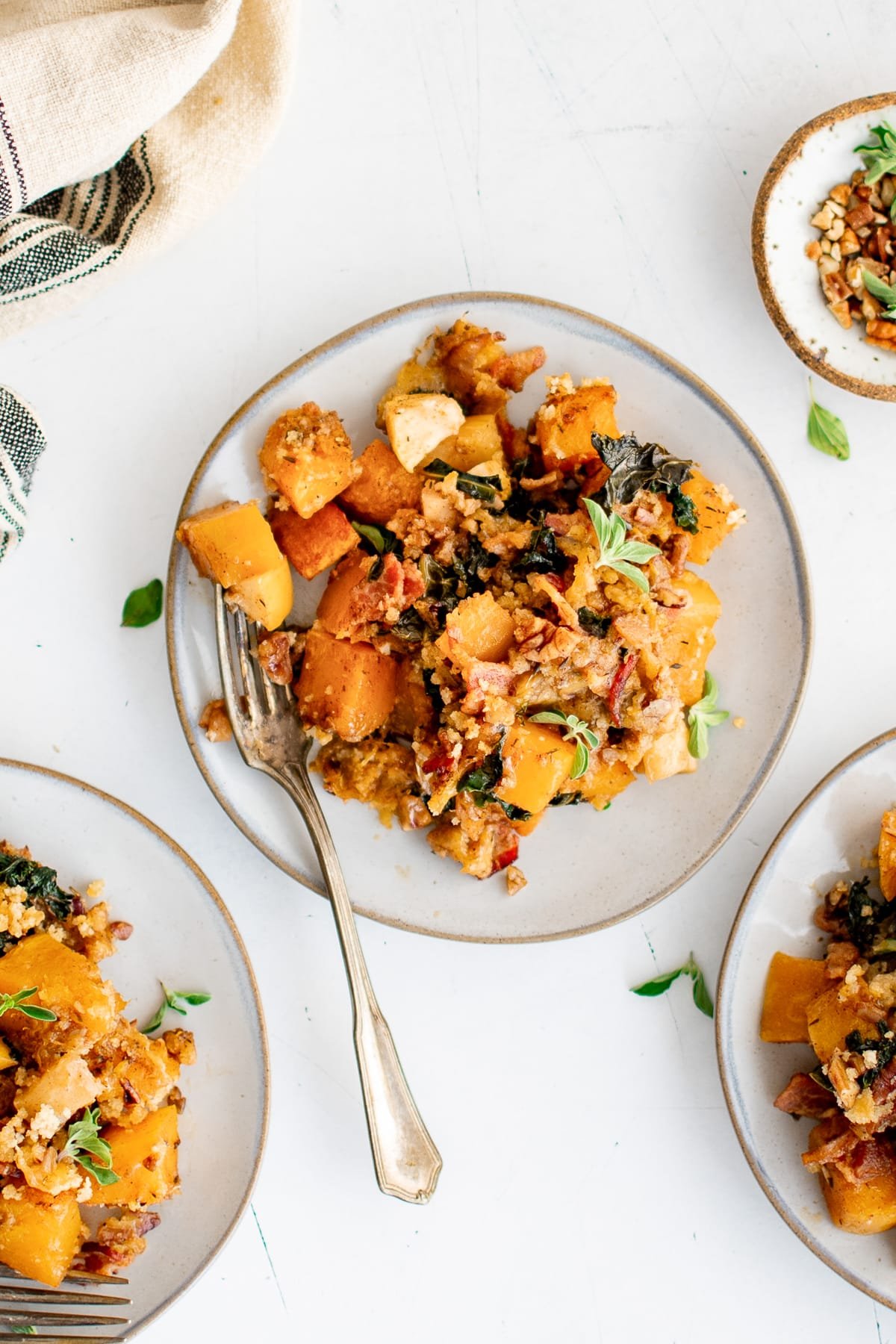 Plate of baked butternut squash casserole with greens, breadcrumbs, and crispy bacon.