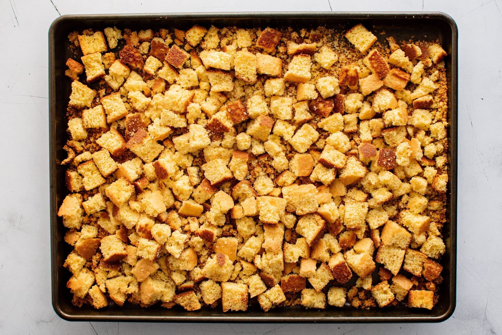 Golden toasted cornbread cubes on a baking sheet, ready for mixing with the sausage mixture