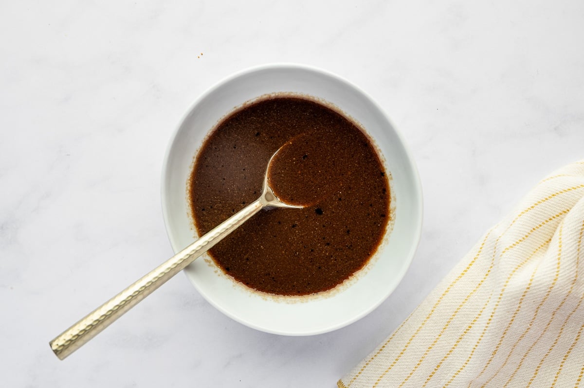 Honey balsamic vinaigrette whisked in a white bowl with a spoon.