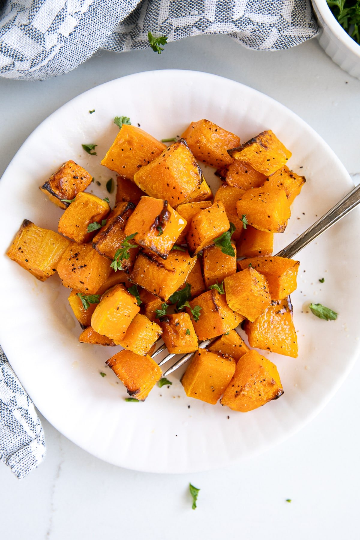 Plate of roasted butternut squash cubes garnished with parsley.