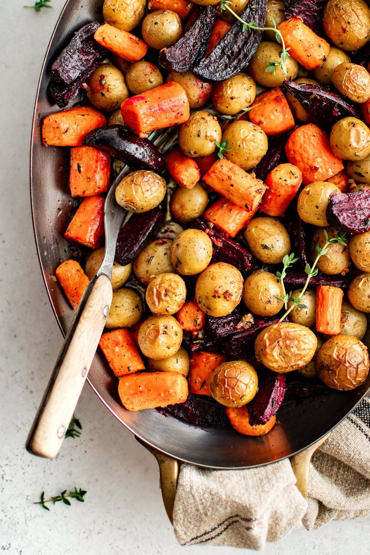 Close-up of roasted root vegetables garnished with thyme. Flavorful and easy Thanksgiving side dish.
