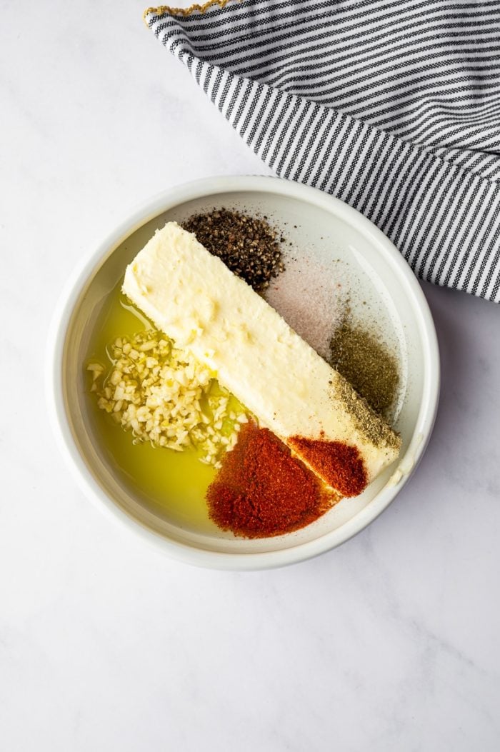 Butter, olive oil, garlic, paprika, salt, and pepper in a bowl for making herb butter for roast turkey recipe.