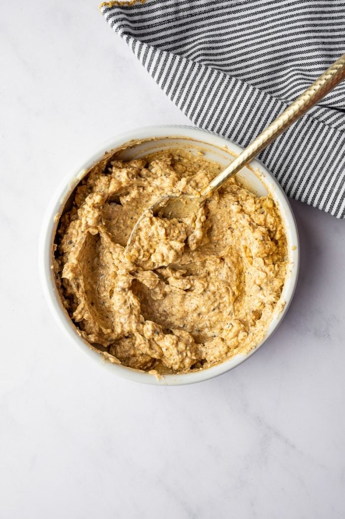 Creamy garlic herb butter mixture in a white bowl for coating Thanksgiving turkey before roasting.