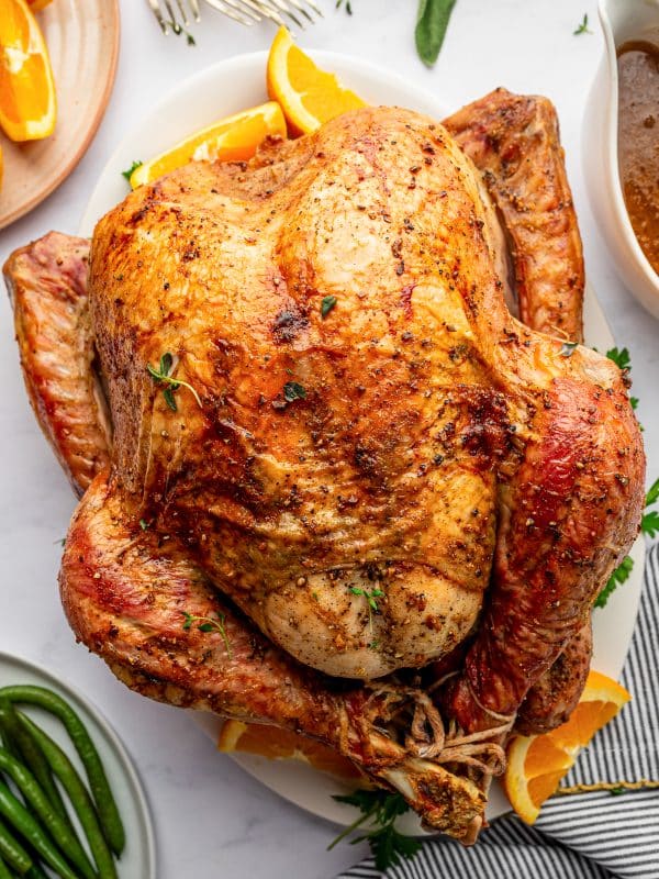 Golden roasted Thanksgiving turkey on a serving platter with oranges and herbs