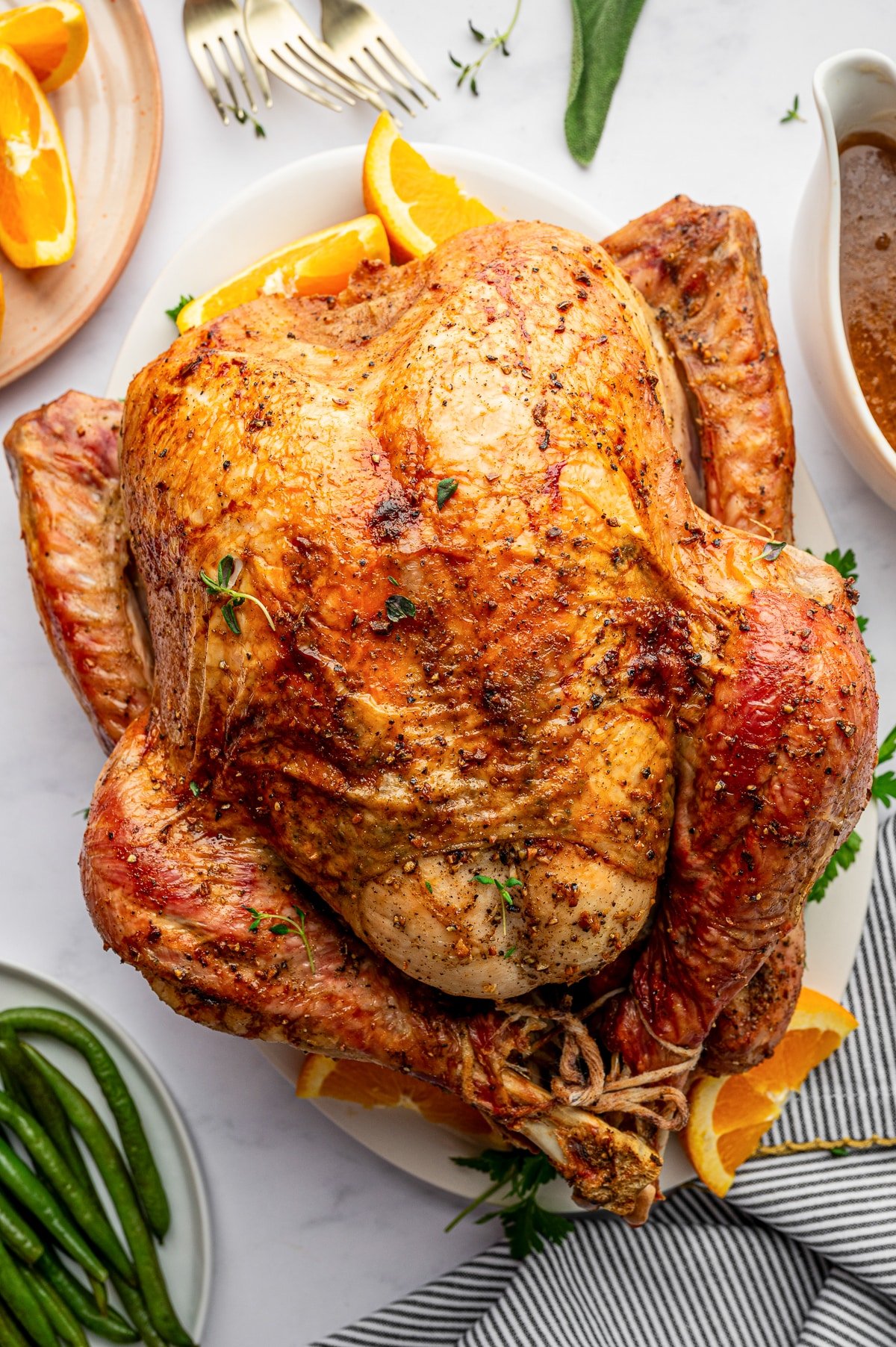 Golden roasted Thanksgiving turkey on a serving platter with oranges and herbs
