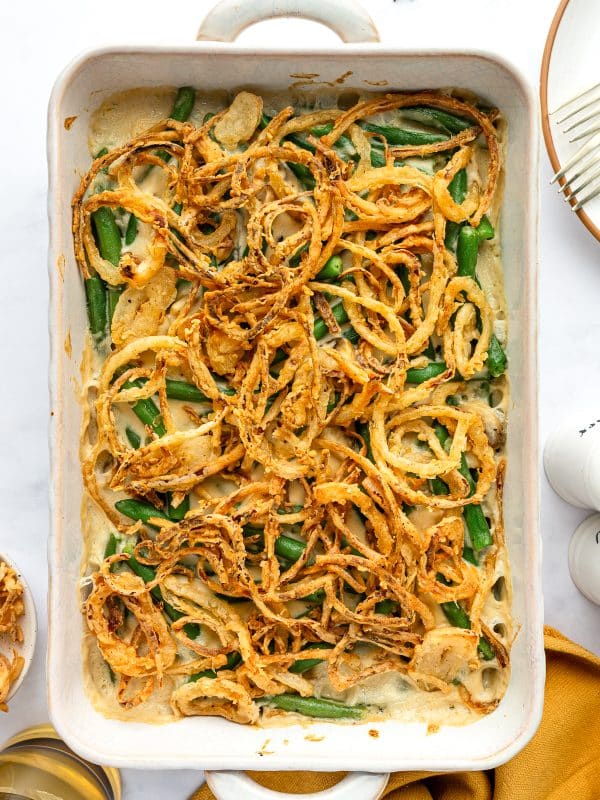 Freshly baked green bean casserole with crispy golden onions in a white baking dish.