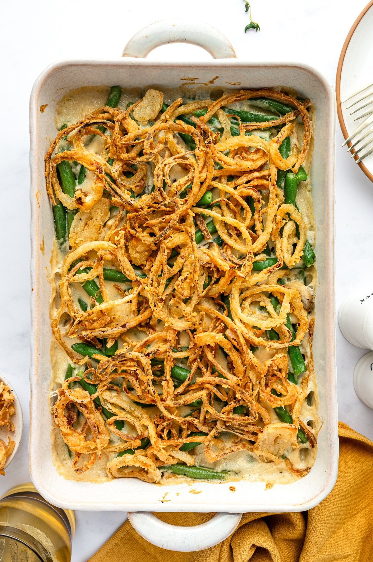 Freshly baked green bean casserole with crispy golden onions in a white baking dish.