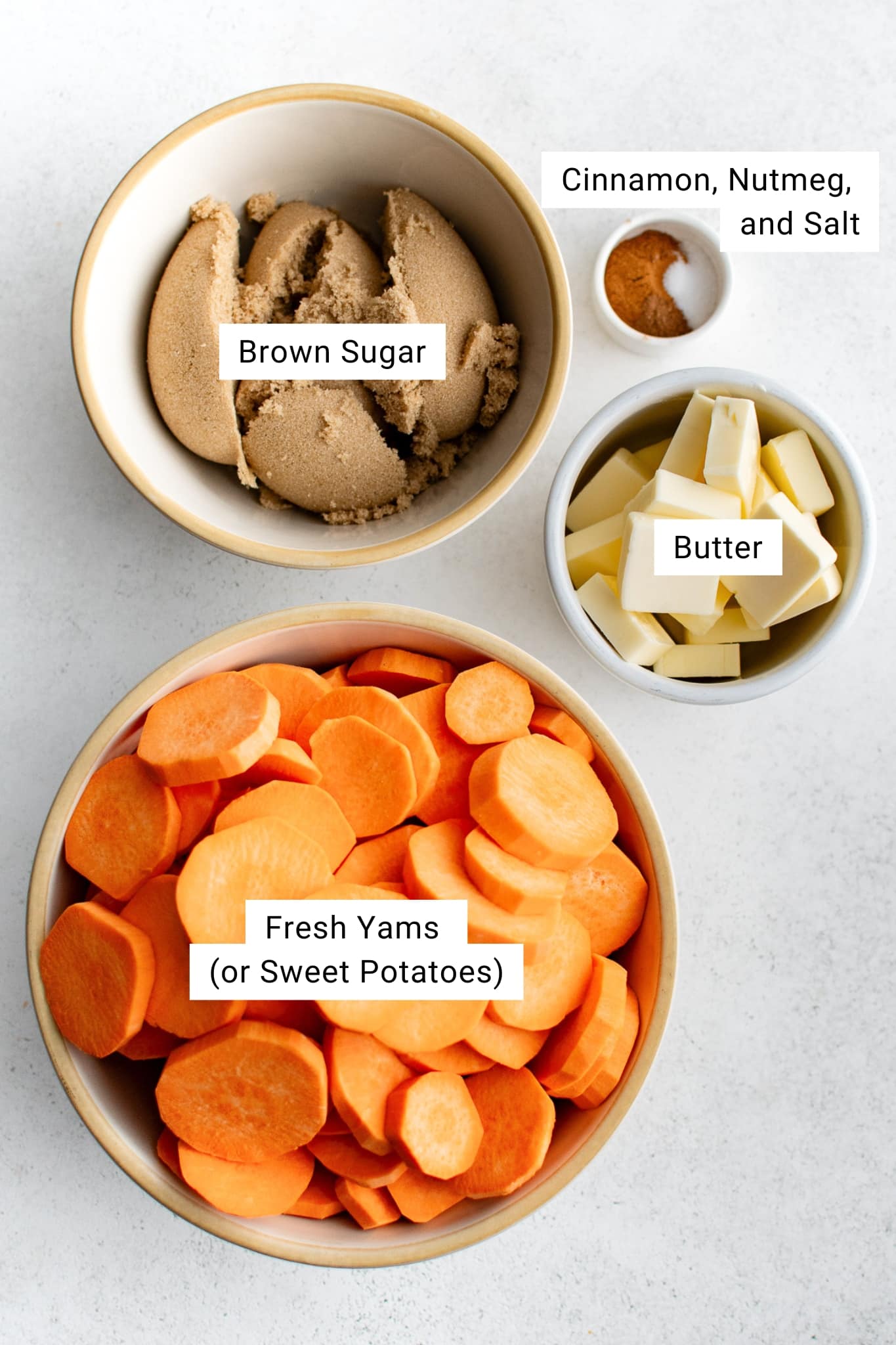 Bowls of ingredients for making candied yams including sliced yams, brown sugar, butter, and a small dish of cinnamon, nutmeg, and salt.
