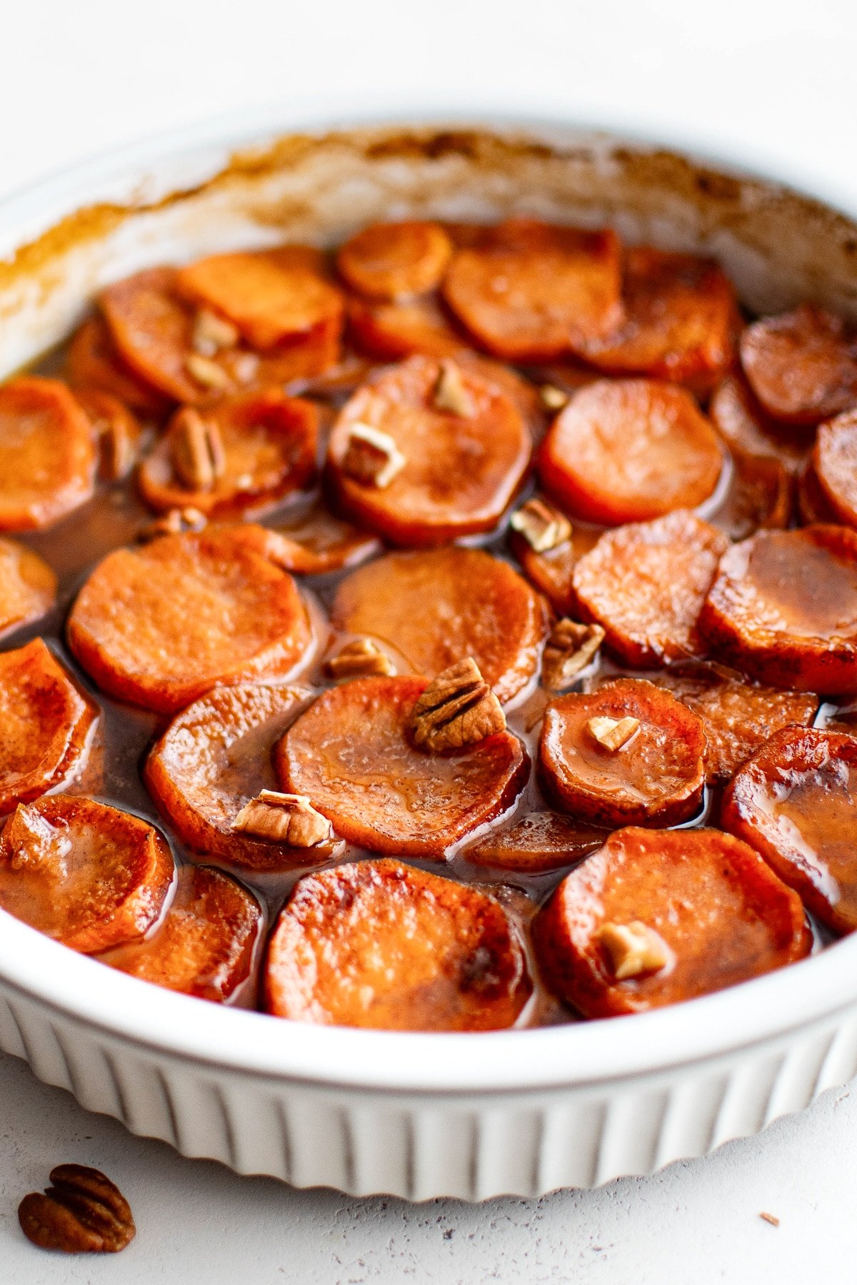 Side view of baked candied yams in a white baking dish.