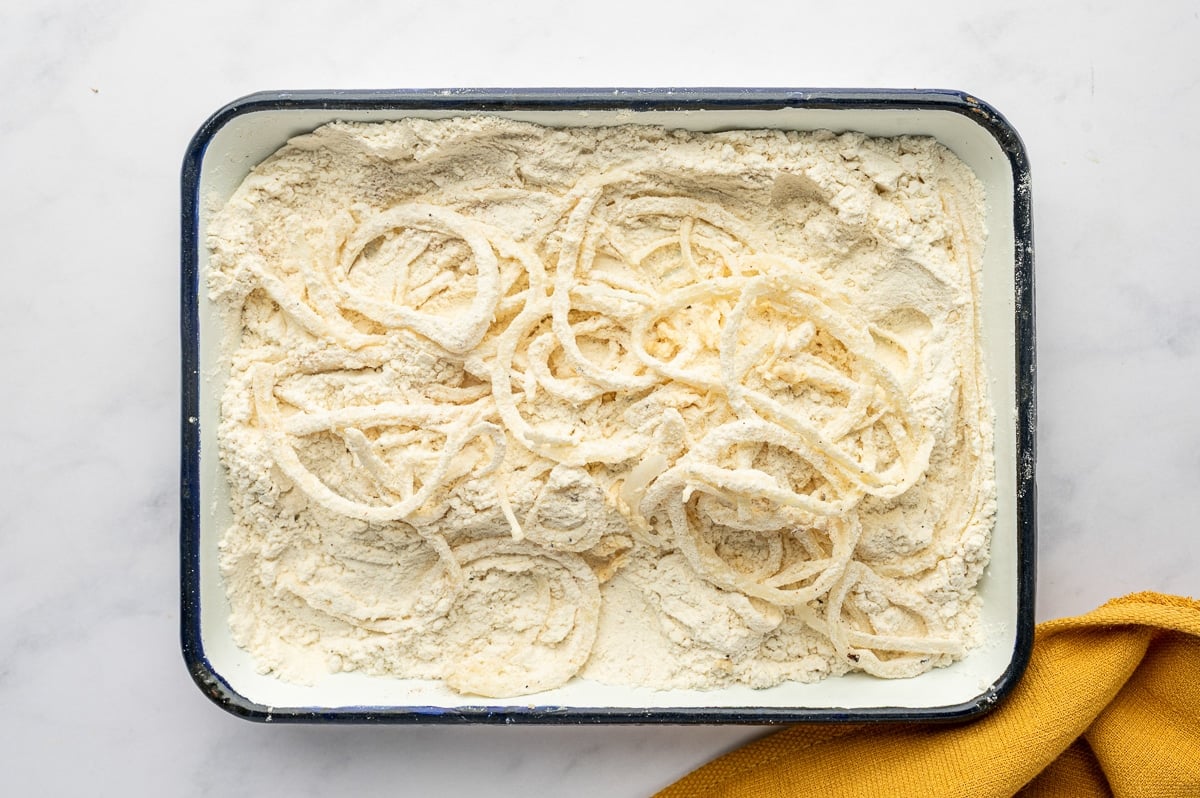 Onions dredged in seasoned flour, ready to be fried.