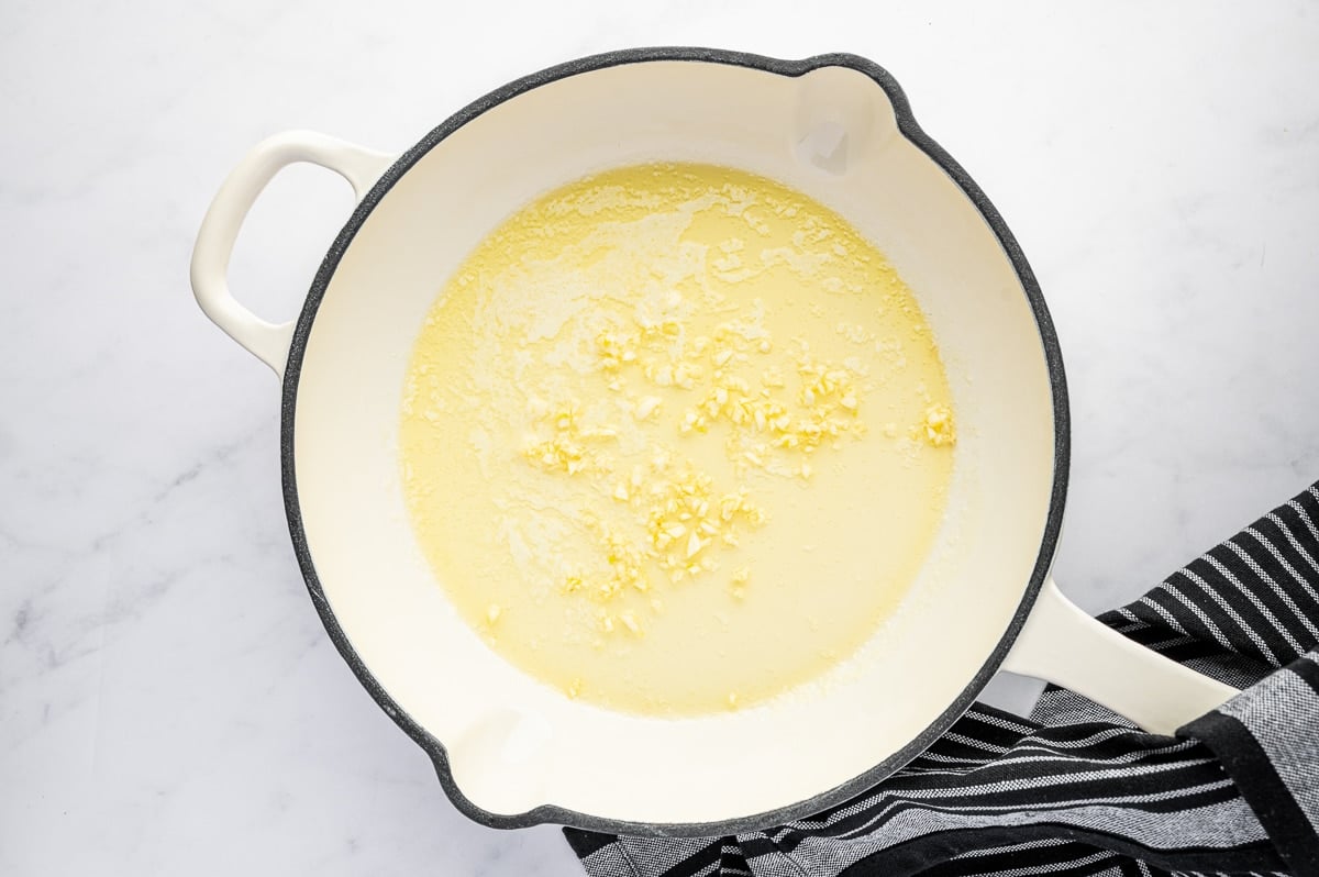 Butter melting in a skillet with minced garlic to make homemade gravy from scratch.