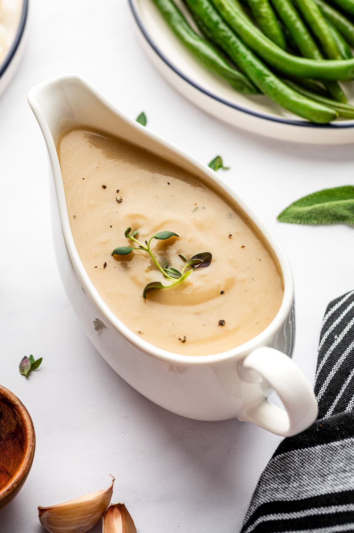 Smooth homemade gravy served in a white gravy boat and garnished with herbs.