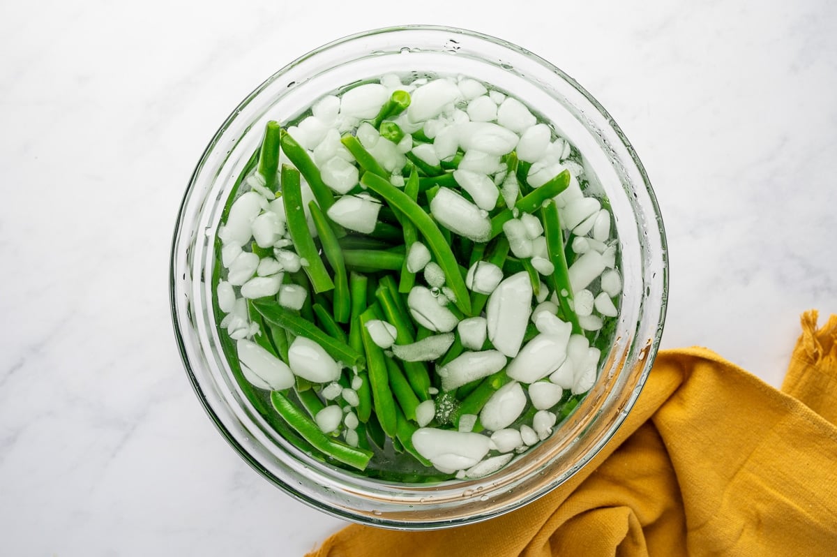 Fresh green beans cooling in an ice water bath after blanching.