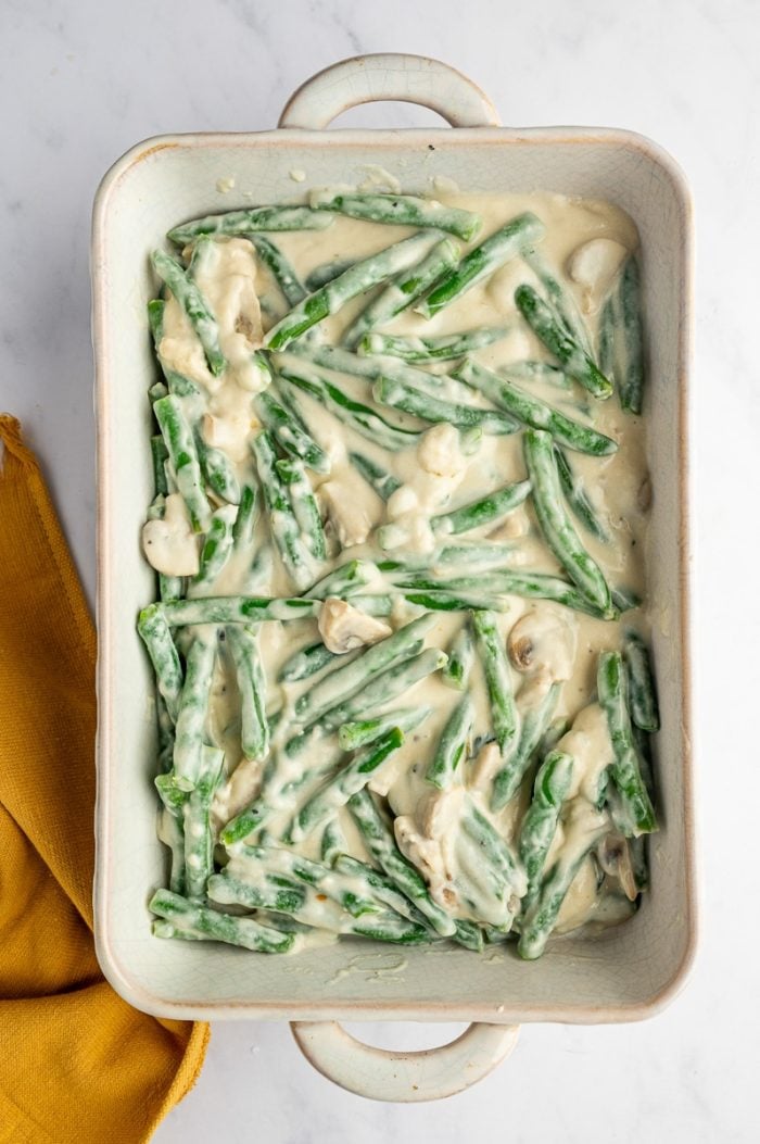 Green bean casserole mixture spread evenly in a baking dish before adding fried onions.