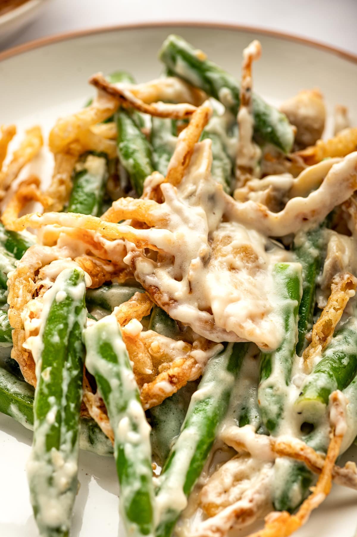 erving of fresh green bean casserole on a plate with creamy sauce and crispy onions.
