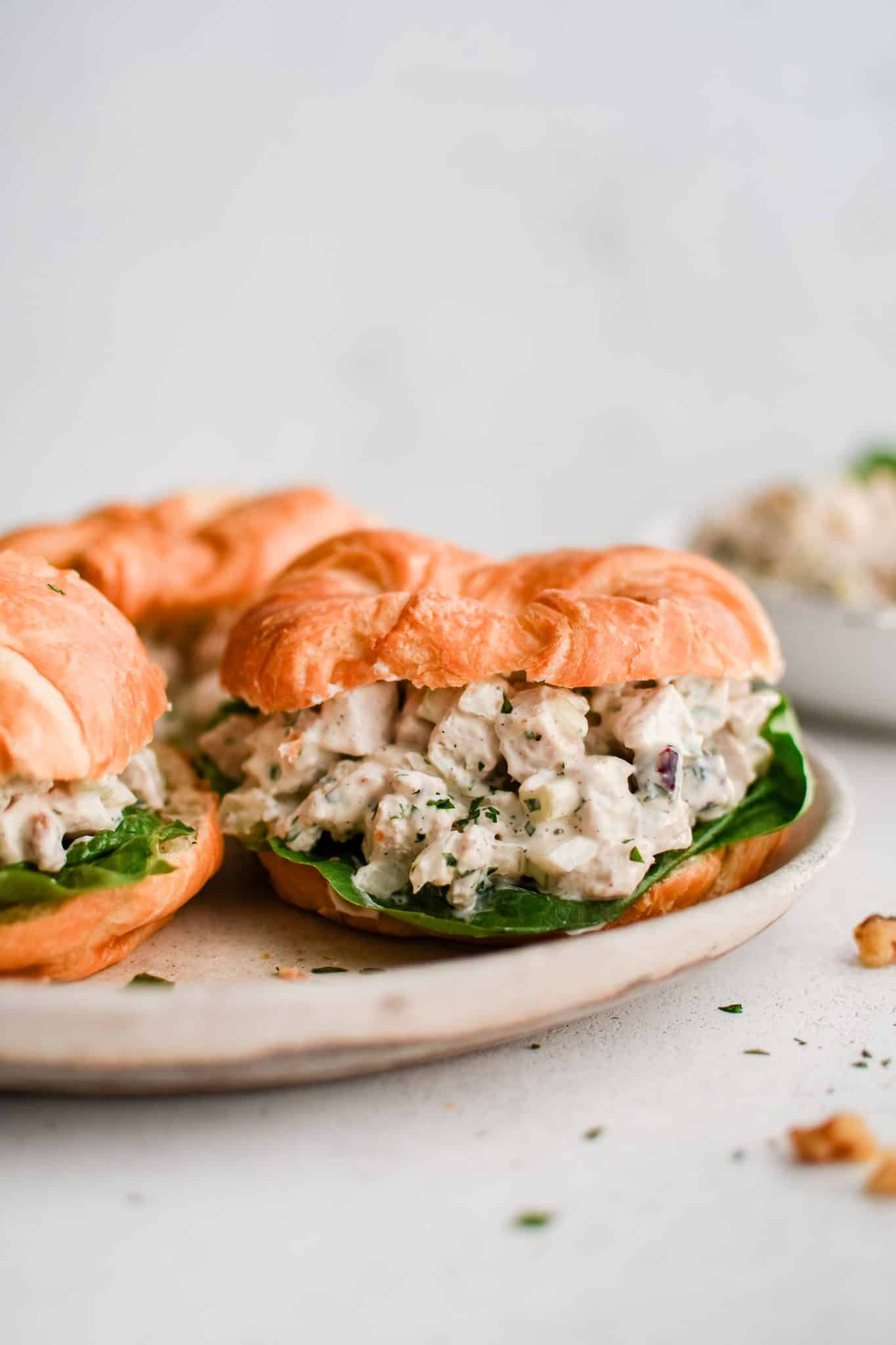 Close-up of a turkey salad croissant sandwich with lettuce on a plate.