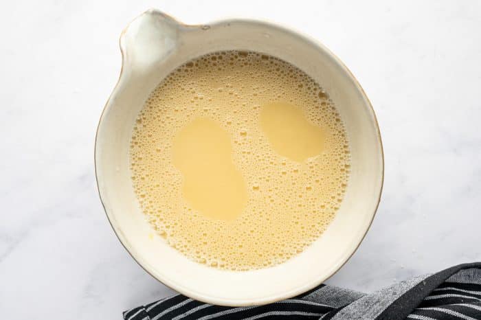 Whisked eggs combined with broth in a ceramic bowl.