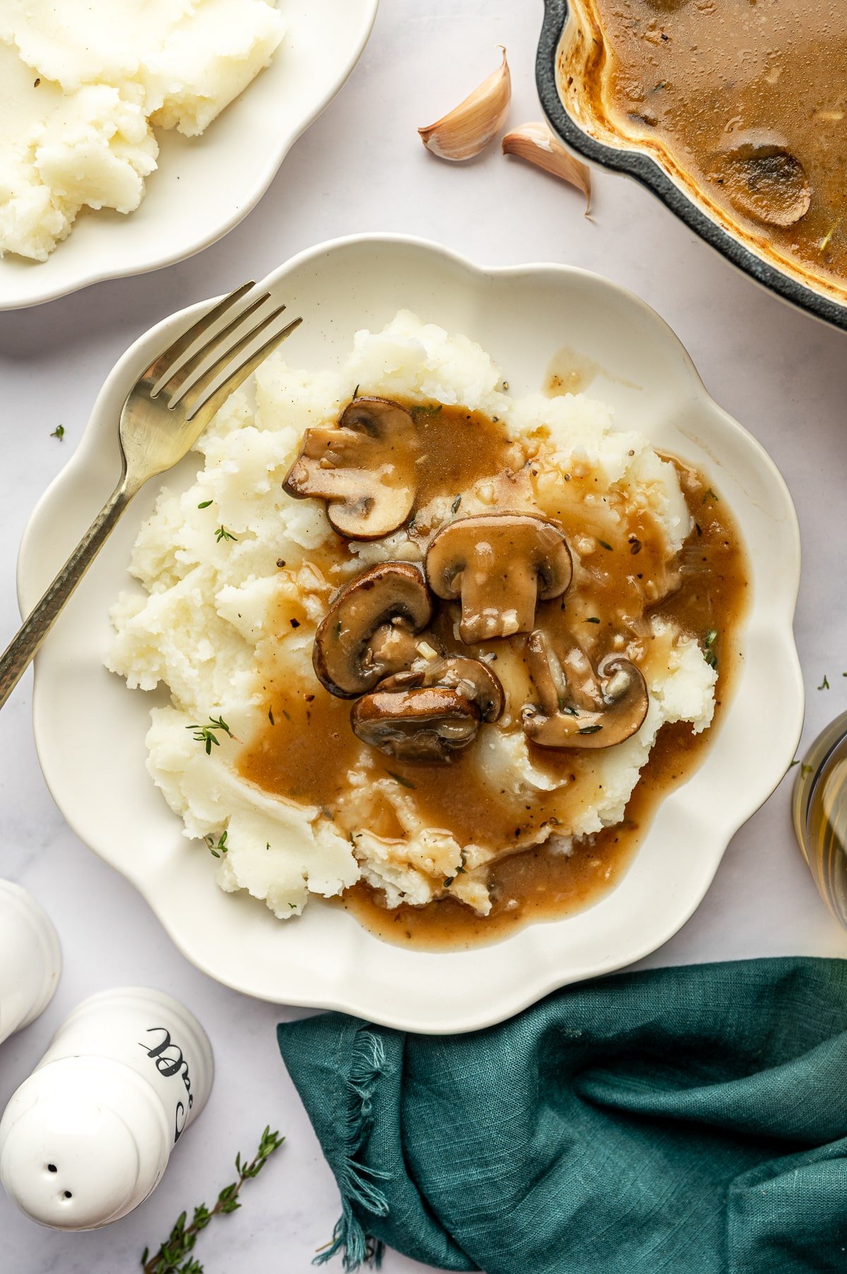 Plate of mashed potatoes topped with mushroom gravy and sliced mushrooms.