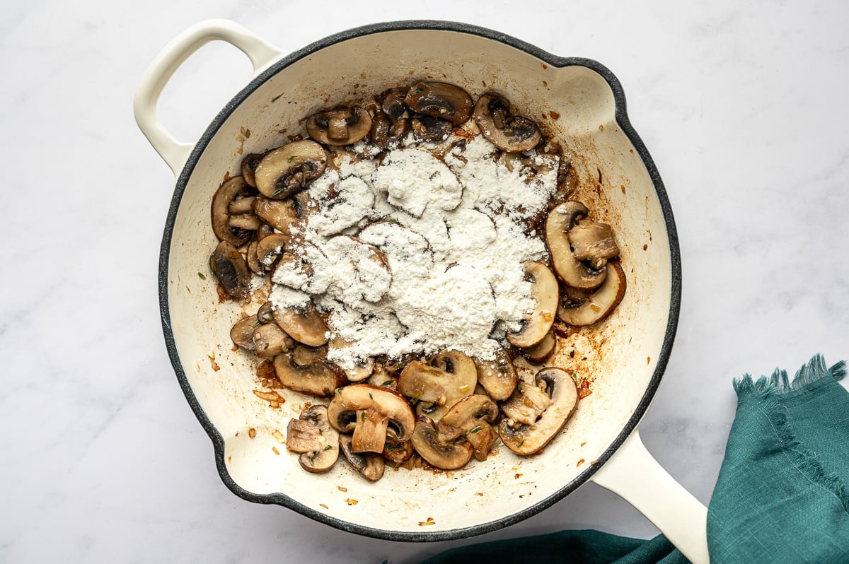Browned mushrooms coated with a layer of flour in a skillet to make a roux for gravy.