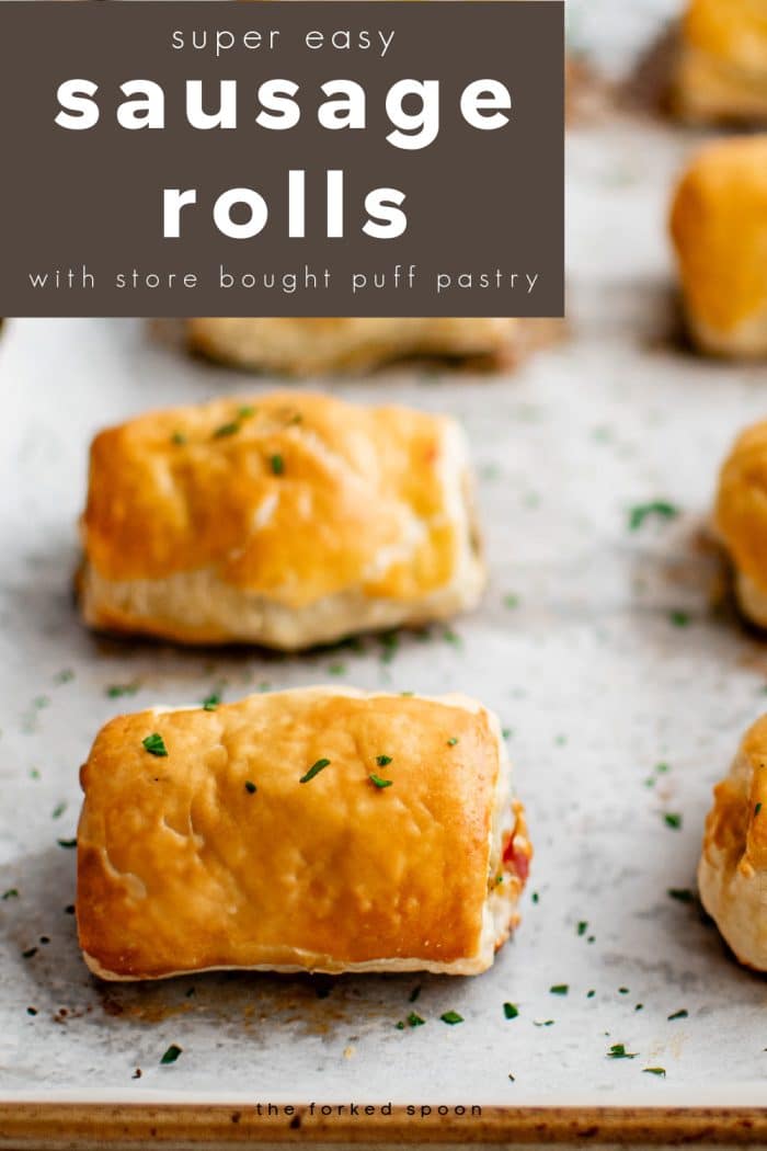 Pinterest friendly vertical image showing flaky, golden sausage rolls on parchment lined baking sheet. A bold text block at the top reads โsuper easy sausage rolls with store bought puff pastryโ and theforkedspoon.com appears along the bottom edge.