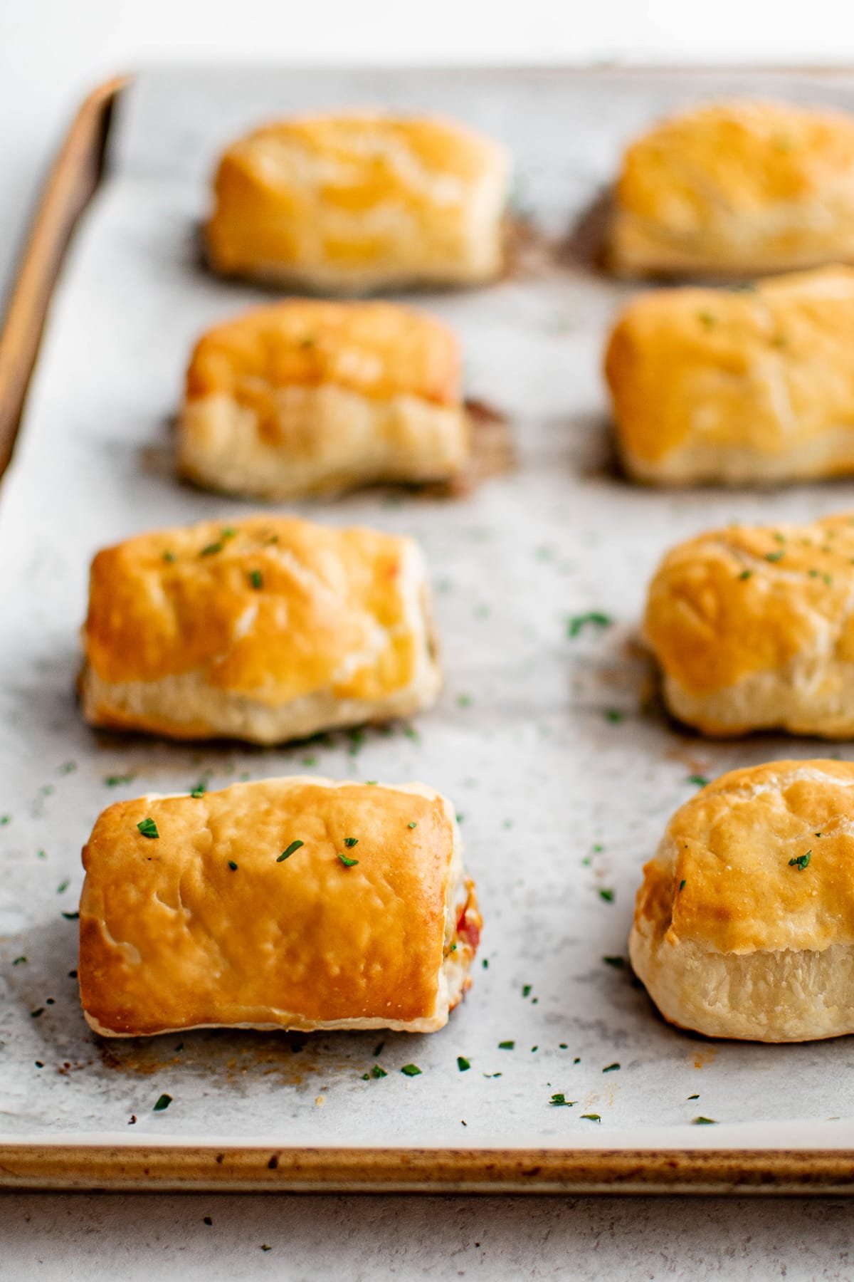 Closeup overhead view of freshly baked golden sausage rolls on parchment.