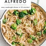 Vertical Pinterest-style image of chicken broccoli Alfredo in a large white skillet with pale green handles. The pasta is creamy and mixed with bite-sized chicken pieces and bright green broccoli florets. A large light gray text box overlays the top left corner with black text that reads โCHICKEN BROCCOLI ALFREDOโ and smaller text underneath that reads โeasy weeknight dinner in 35 minutes!โ The words โthe forked spoonโ appear at the bottom.