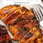 Vertical Pinterest graphic showing sliced balsamic grilled chicken breast with dark caramelized grill marks, chopped parsley, lime wedges, and a silver fork. A large white text box at the top reads "The Best Grilled Chicken Recipe" in black letters, with "THEFORKEDSPOON.COM" below.