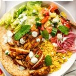 Vertical Pinterest pin featuring a large white chicken shawarma bowl with yellow rice, sliced chicken, romaine, cucumber tomato salad, pink pickled onions, tzatziki, mint, parsley, and pita beneath the text "Chicken Shawarma Bowls" and "with yellow rice, fresh veggies, and tzatziki," with "THEFORKEDSPOON.COM" at the bottom.