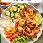 Vertical Pinterest pin showing a large ivory scalloped bowl filled with white rice, browned shrimp, diced cucumber, matchstick carrots, green edamame, sliced green onions, sesame seeds, a lime wedge, and creamy spicy mayo. A large white text box across the top reads "Shrimp Rice Bowl" in black lettering, followed by a thin aqua line and the smaller text "+ spicy mayo sauce." Black text along the bottom reads "THEFORKEDSPOON.COM."