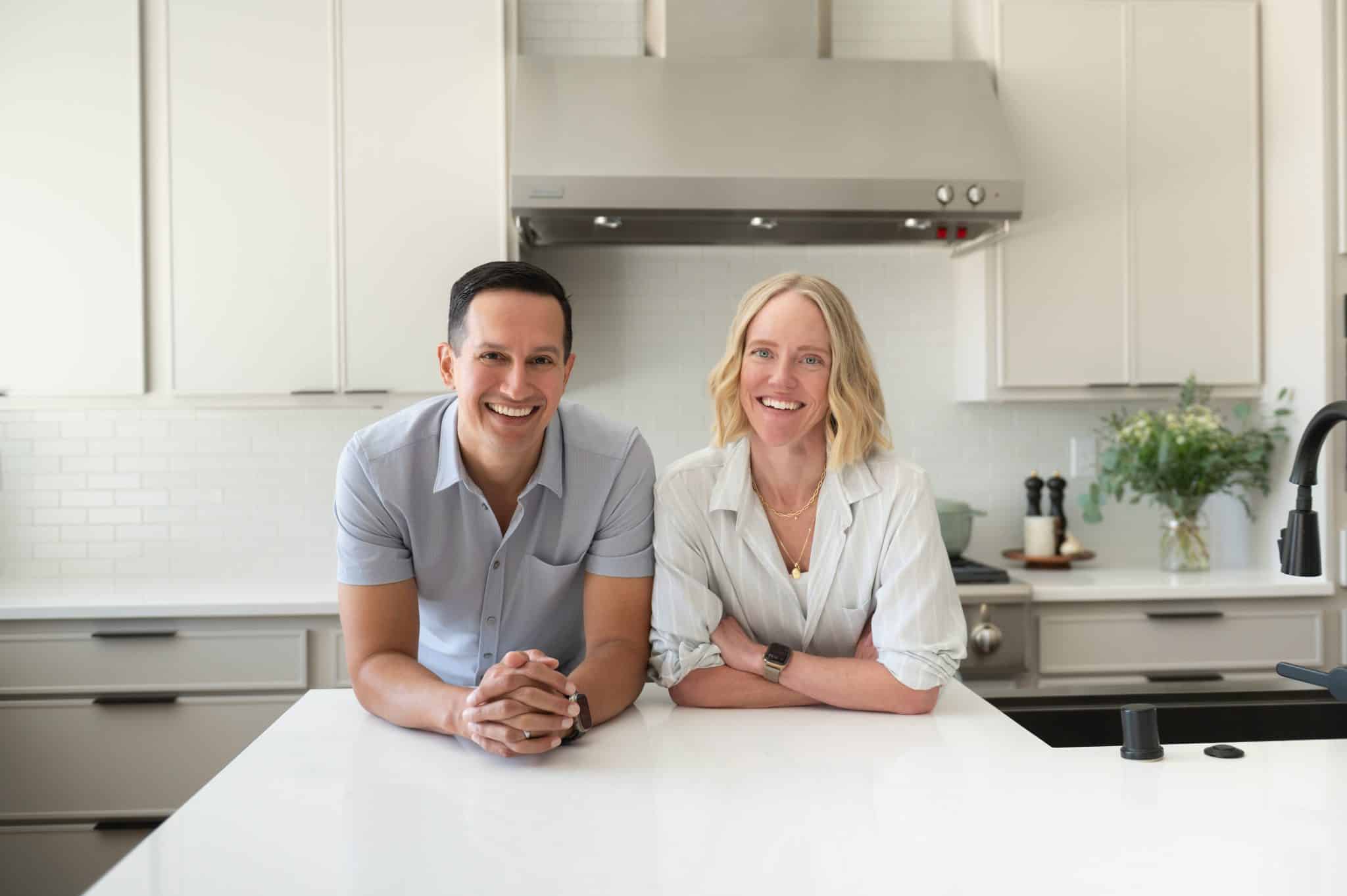 Jessica and Aaron Randhawa, founders of The Forked Spoon, standing together in their bright home kitchen.