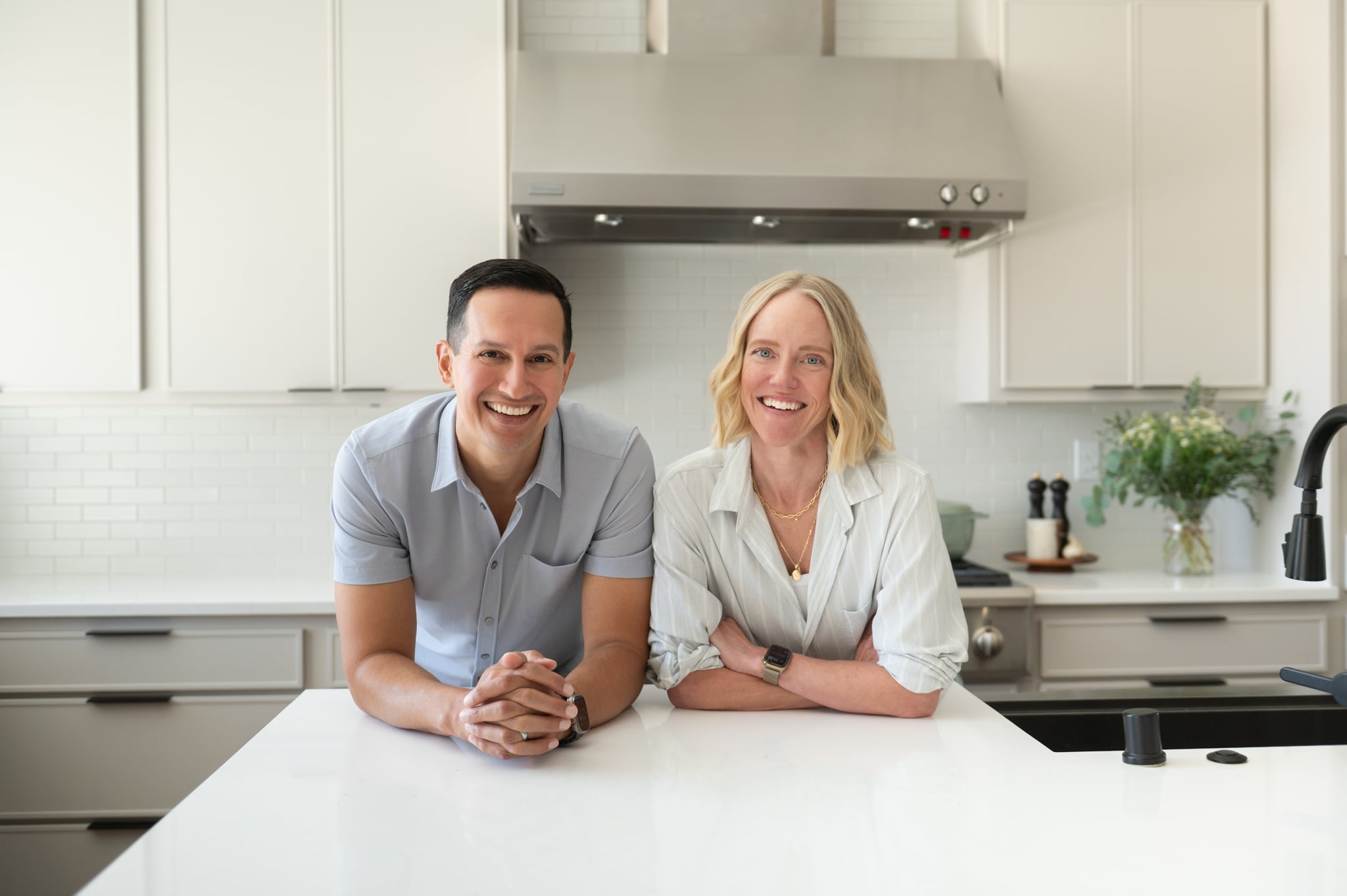 Jessica and Aaron Randhawa, founders of The Forked Spoon, standing together in their bright home kitchen.