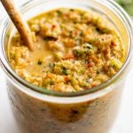 Jar filled with vibrant homemade sofrito with a wooden spoon resting inside