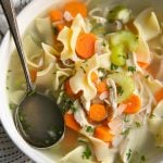 White bowl filled with homemade chicken noodle soup made with carrots, celery, and chicken and noodles.