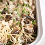 White baking dish filled with homemade turkey tetrazzini and topped with melted white cheddar cheese.